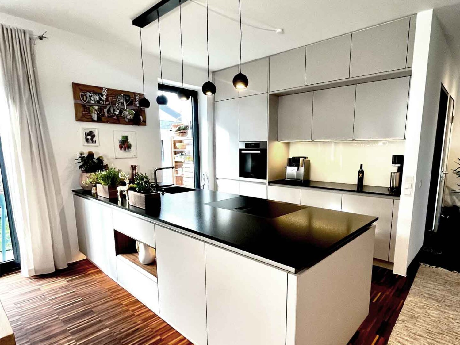 Designerküche mit weißen Fronten und schwarzer Arbeitsplatte mit LED-Beleuchtung