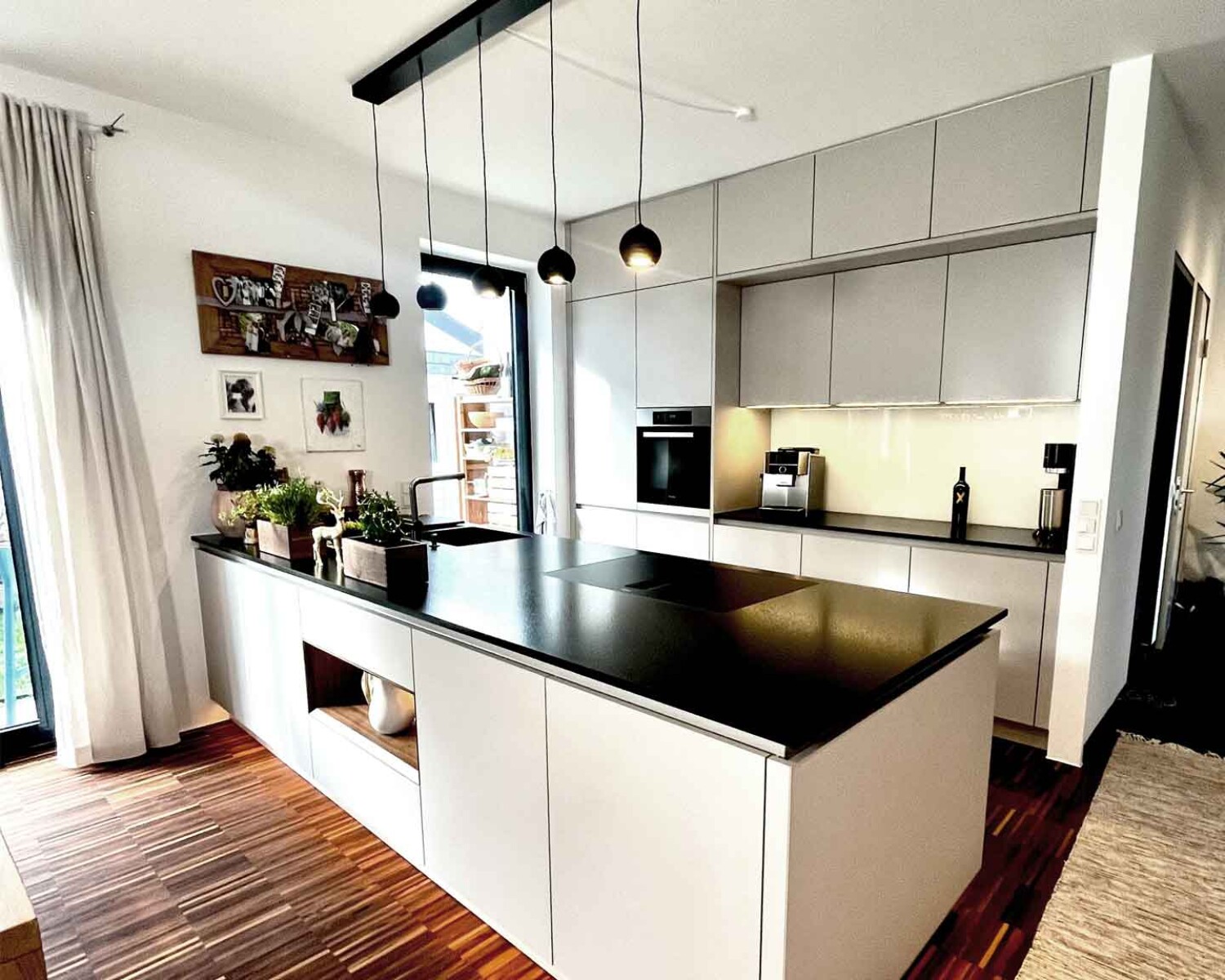 Designerküche mit weißen Fronten und schwarzer Arbeitsplatte mit LED-Beleuchtung