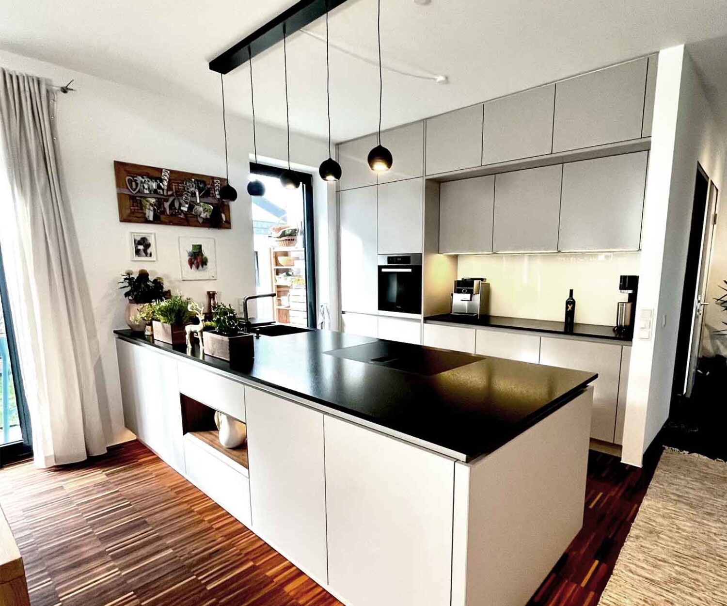 Designerküche mit weißen Fronten und schwarzer Arbeitsplatte mit LED-Beleuchtung