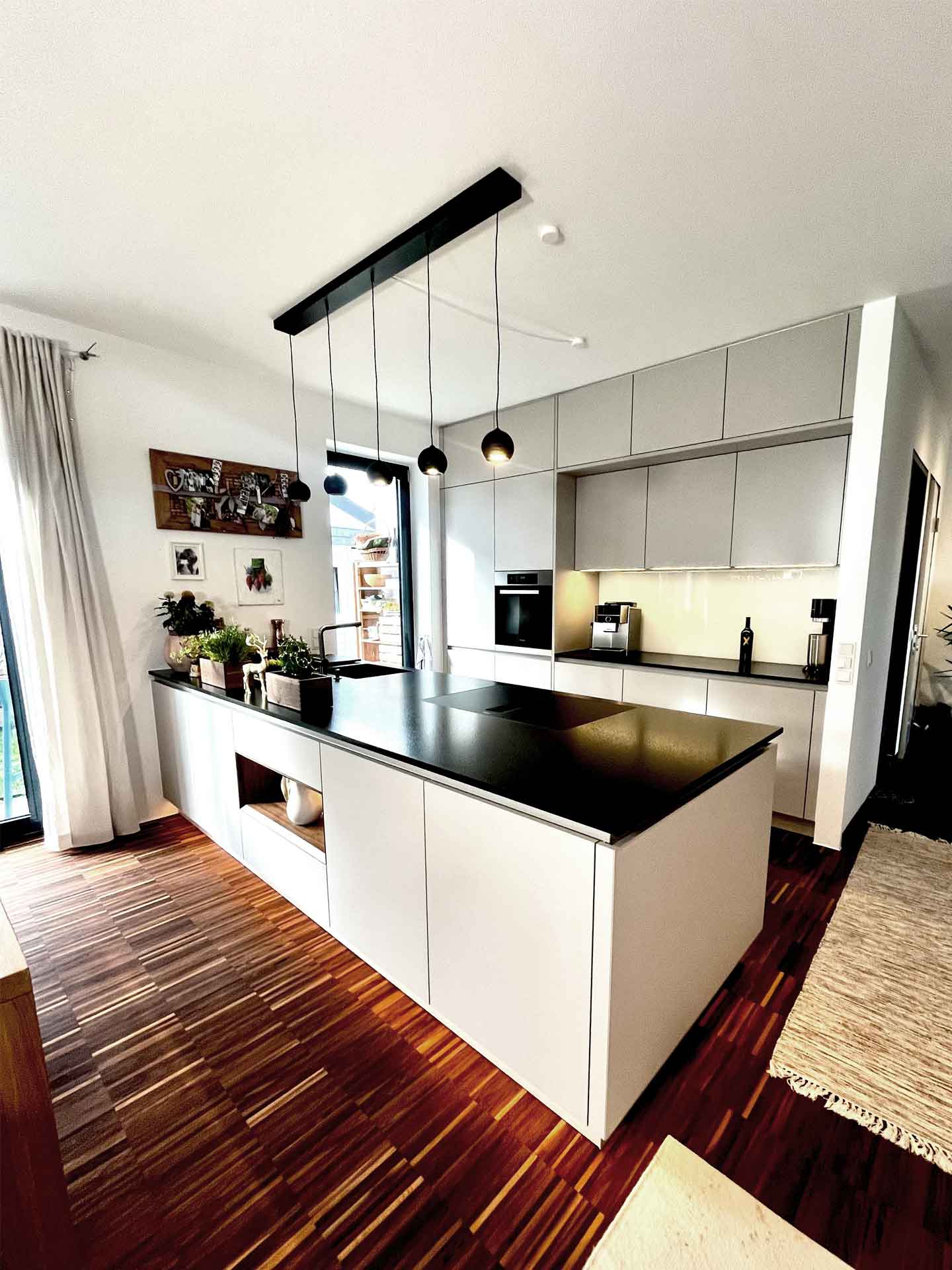 Designerküche mit weißen Fronten und schwarzer Arbeitsplatte mit LED-Beleuchtung