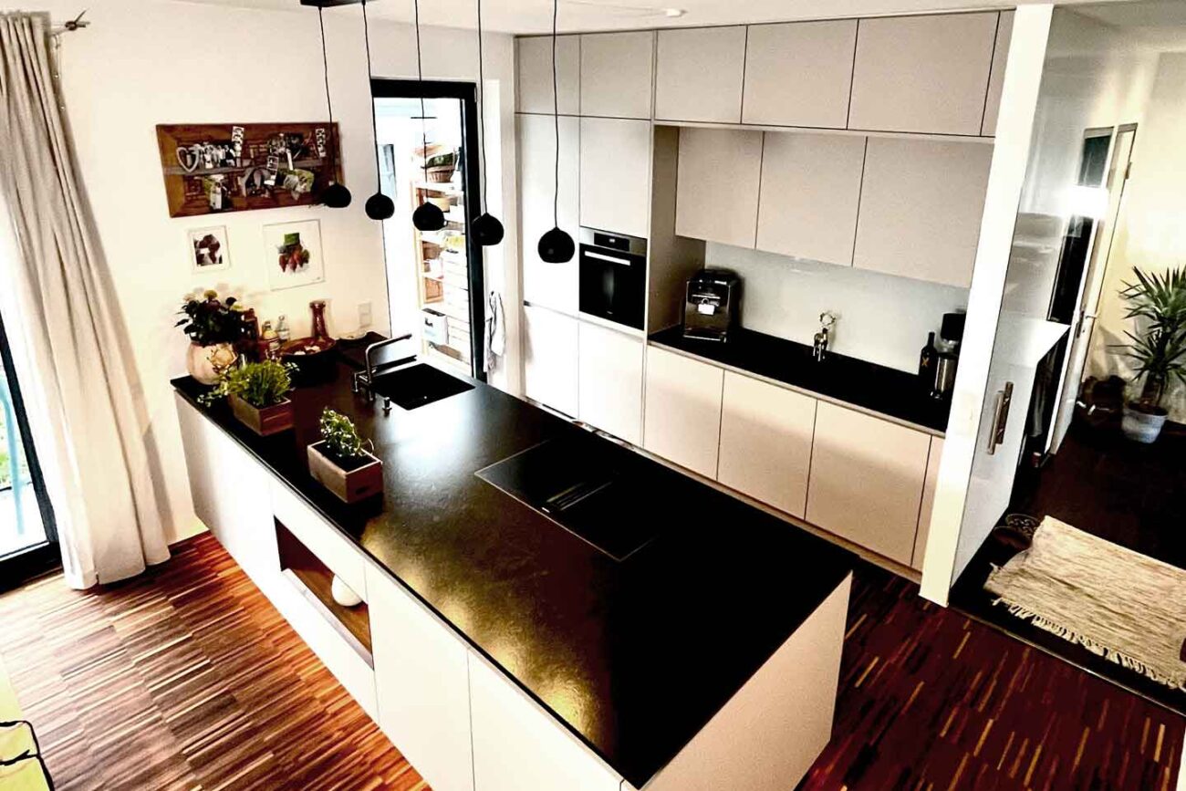 Küche mit weißen Fronten auf einem Stabparkett in Nussholz